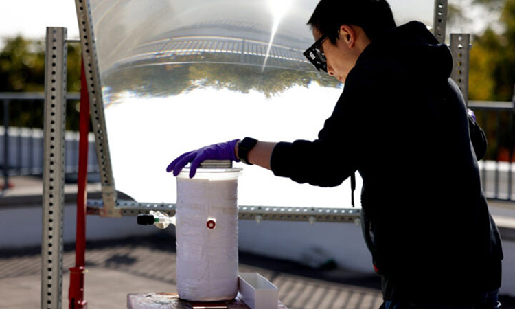 Peng Zhou sử dụng một thấu kính lớn để tập trung ánh sáng mặt trời vào chất xúc tác tách nước